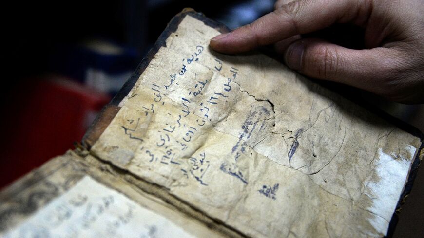 A librarian shows a book from University of Iraq's northern city of Mosul, one of those that escaped destruction at the hands of the Islamic State group