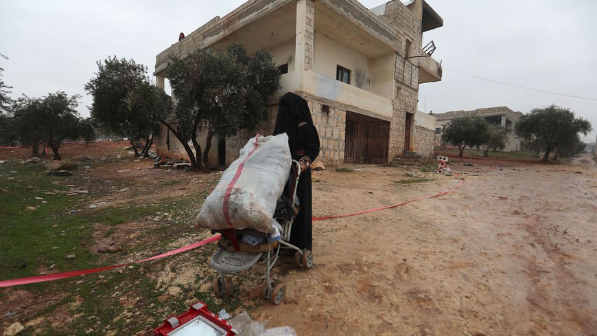 A fully veiled woman collects items near the house in which the leader of Islamic State (IS) group Amir Mohammed Said Abd al-Rahman al-Mawla, aka Abu Ibrahim al-Hashimi al-Qurashi died during a raid by US special forces, in the town of Atme in Syria's northwestern province of Idlib, on Feb. 4, 2022. 