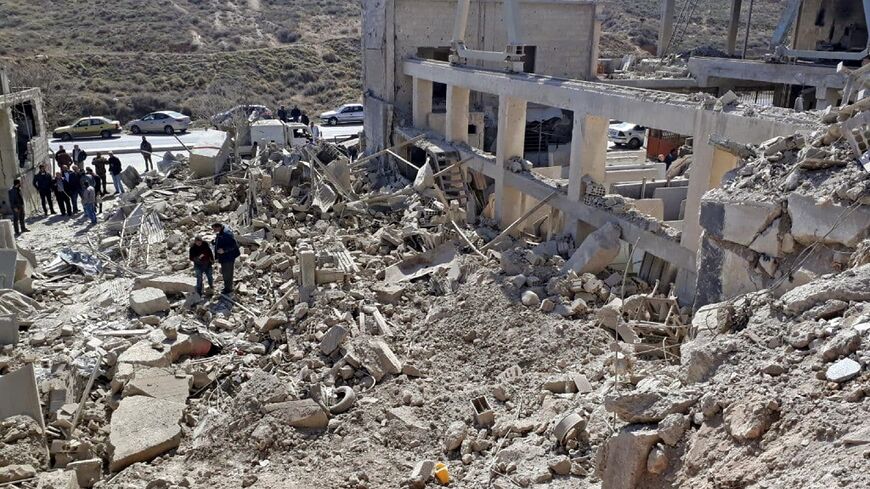 People inspect destroyed and damaged buildings following Israeli missile strikes before dawn near the Syrian capital Damascus