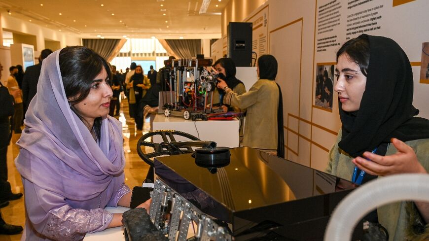 Malala Yousafzai speaks with member of the Afghan Girls Robotics Team at the Doha Forum in the Qatari capital