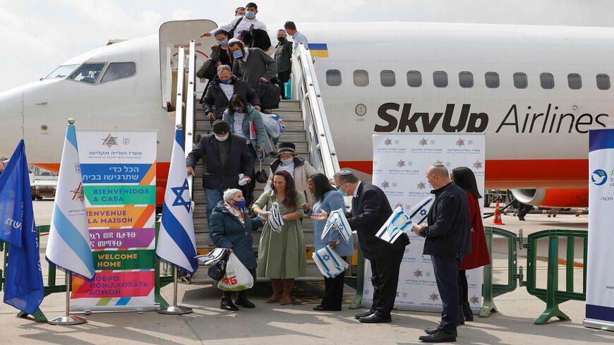 Israeli Minister of Immigration and Absorption Pnina Tamano-Shata (3rd-R) and Yaakov Hagoel (2nd-R), head of the World Zionist Organization, hand out Israeli flags to immigrants from Ukraine disembarking from their aircraft at Ben Gurion Airport in Lod, Israel, Feb. 20, 2022.