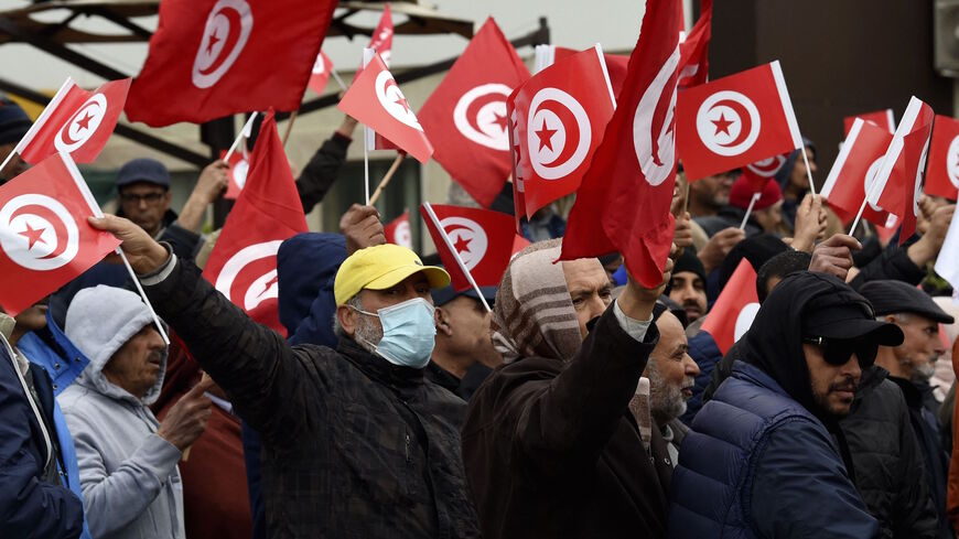 Tunisian protesters raise placards and national flags during a demonstration against their president, not far from the Tunisian Assembly (parliament) headquarters, in the capital Tunis, on March 20, 2022.