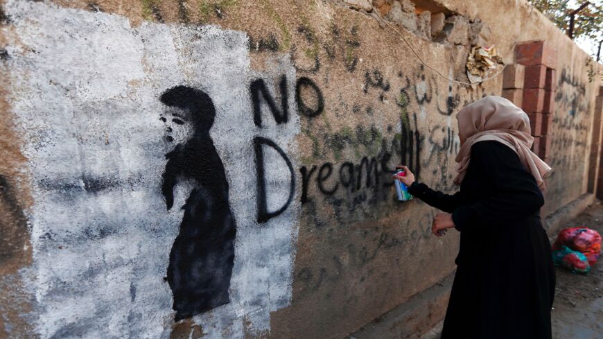 A woman works on a mural on the southern wall of Sanaa's university.