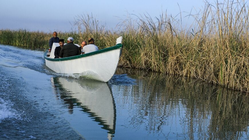 Veterinarian Karrar Ibrahim Hindi (L) sits in an ambulance boat as he heads to treat sick buffaloes, in the marshes of southern Iraq