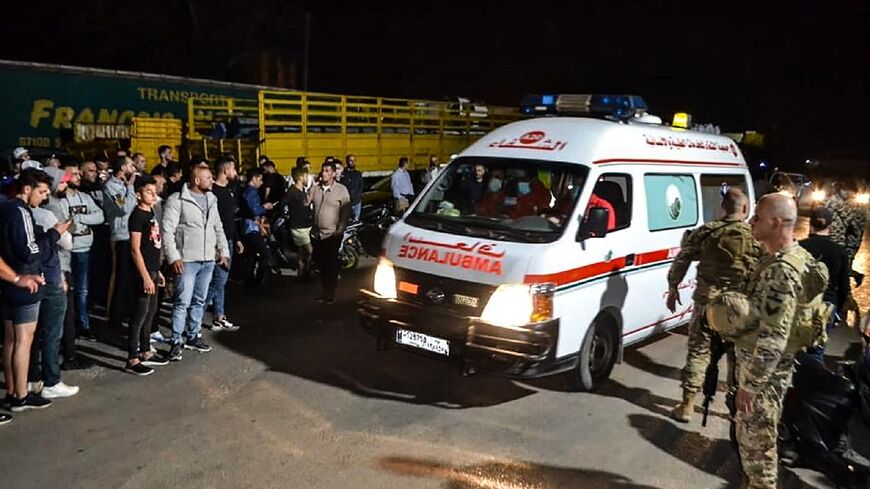 Lebanese soldiers and onlookers stand at the entrance of the port of Tripoli, as an ambulace carries survivors from a boat that sank off the northern city