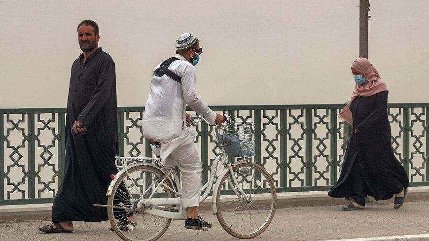 A man rides a bicycle along the Sinek bridge spanning the Tigris river in Iraq's capital Baghdad during a severe dust storm on April 20, 2022