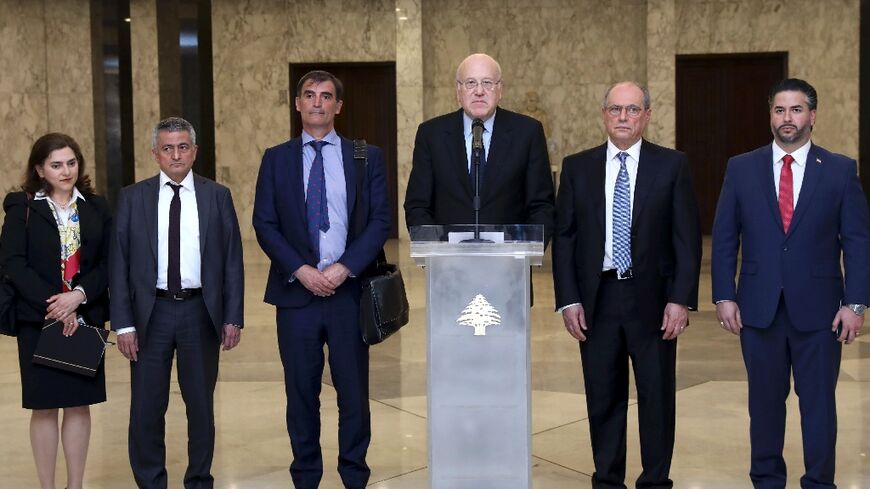 A handout picture provided by the Lebanese photo agency Dalati and Nohra on April 7, 2022 shows Lebanon's Prime Minister Najib Mikati (3rd R) holding a press conference alongside an International Monetary Fund (IMF) delegation 