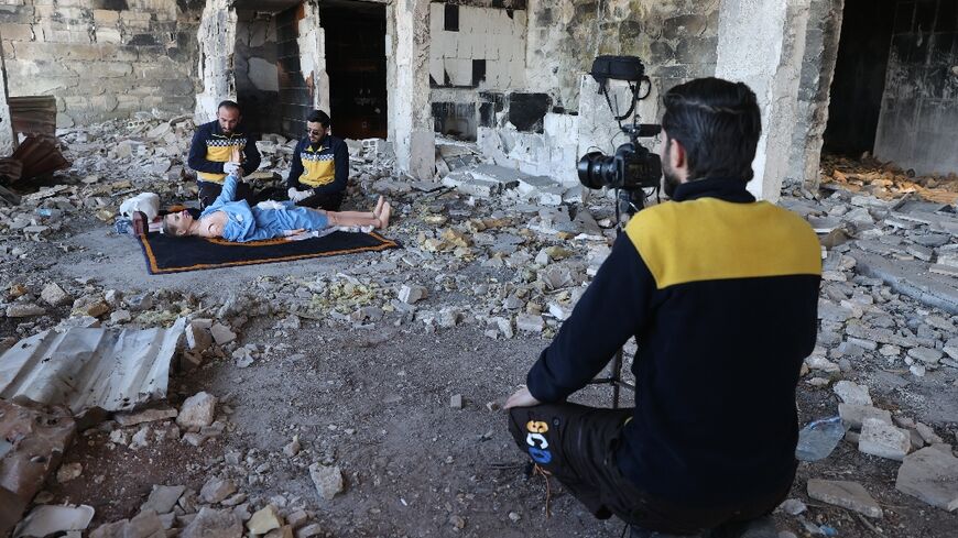 Members of the Syrian civil defence known as the White Helmets use a dummy to demonstrate their rescue skills during a video shoot for an instructive film intended for Ukrainian rescuers, in the war-ravaged Syrian town of Ariha