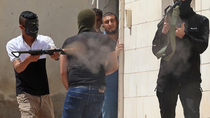 A masked Palestinian man fires an automatic weapon during the latest clashes with Israeli security forces in the West Bank city of Jenin