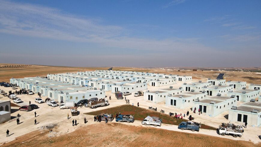 Displaced Syrians arriving with their belongings in a convoy of trucks at a new housing complex.