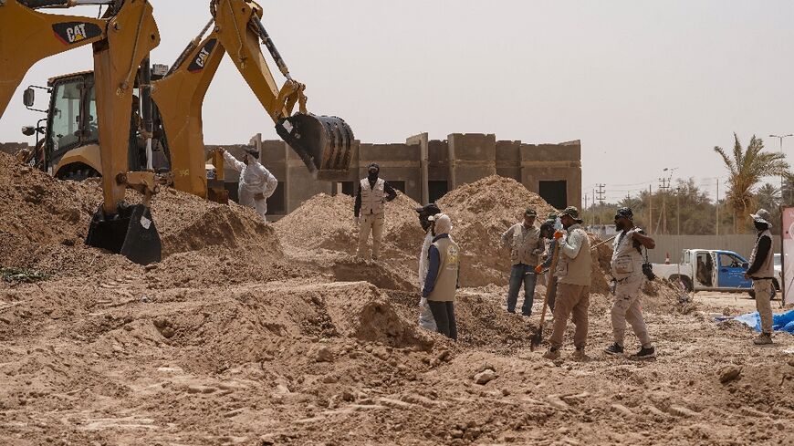 A backhoe digs up earth at the site of a mass grave, discovered by chance when property developers wanted to prepare the land for construction, in the central city of Najaf