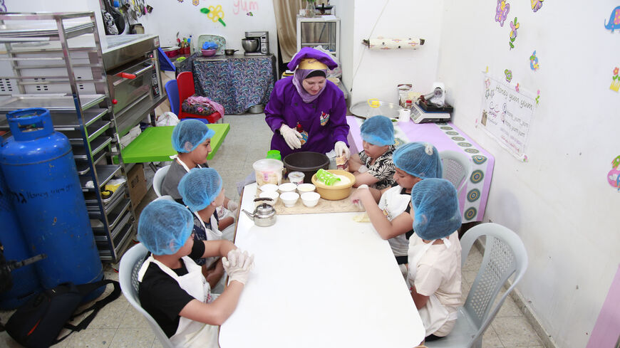 Gazan chef Nagham Skaik teaches a group of children at the Honey Yum Yum summer camp, Gaza Strip, June 2022.