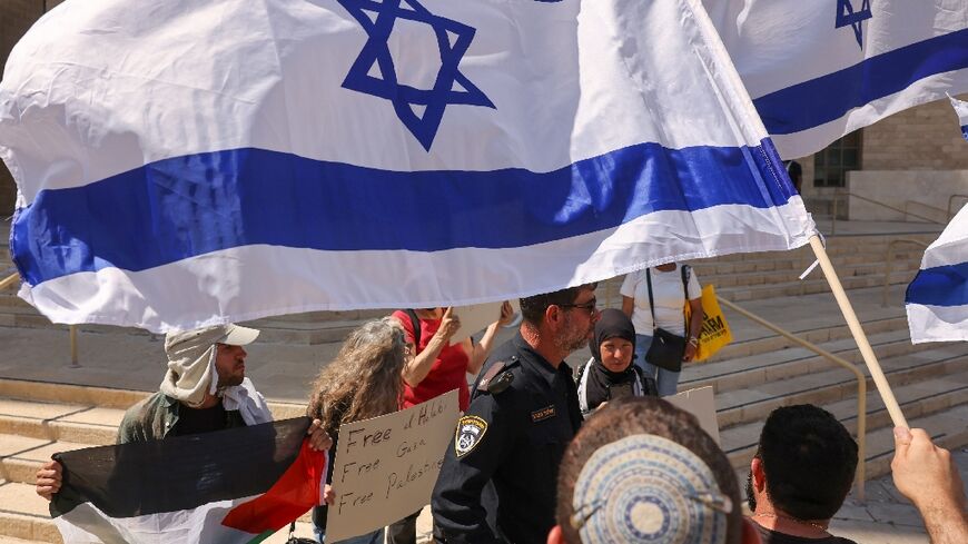 Left-wing activists holding placards and a Palestinian national flag, and right-wing protesters argue outside an Israeli court during the trial of Palestinian Mohammed al-Halabi, the former Gaza director of World Vision, in Beersheba