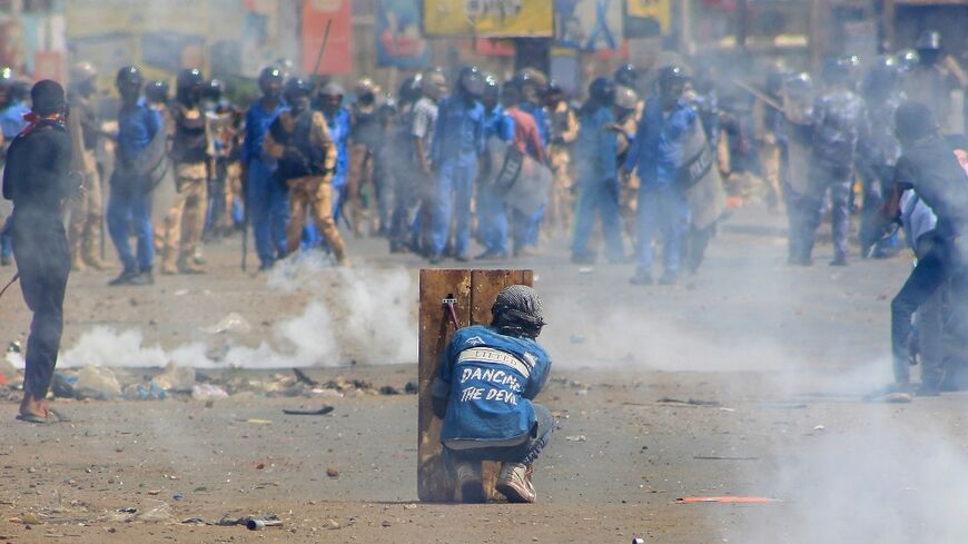 A Sudanese protester takes cover on Thursday from tear gas fired by security forces amid clashes in the Khartoum Bahri twin city of the Sudanese capital