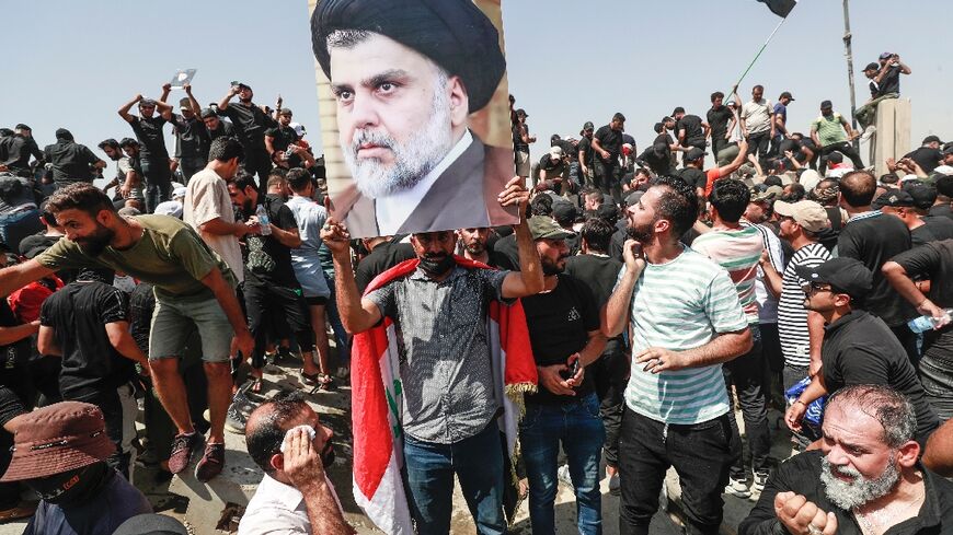 Supporters of the Iraqi cleric Moqtada Sadr raise a portrait of their leader, as they protest at a rival bloc's nomination for prime minister