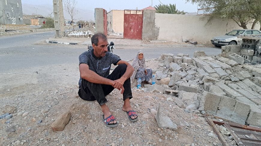 A couple sits in the rubble after earthquakes struck the village of Sayeh Khosh in Iran's southern Hormozgan province