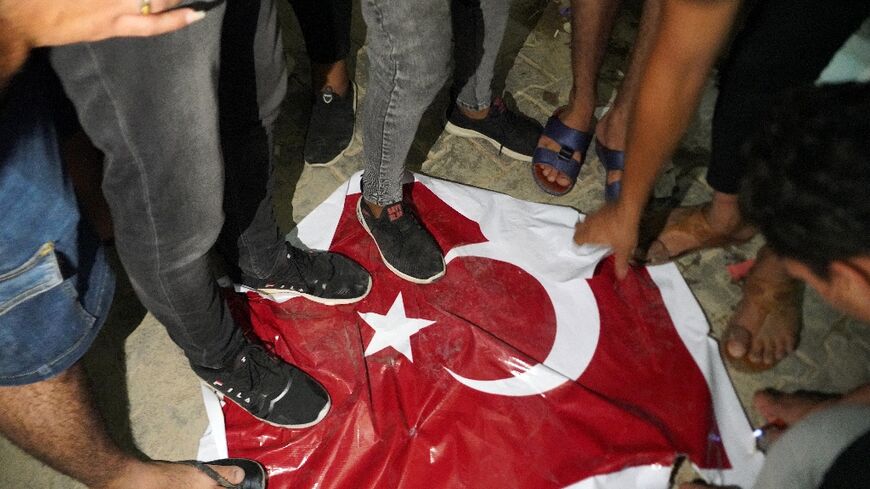 Iraqi protesters trample on a Turkish flag outside the consulate in the Shiite shrine city of Najaf, angry at the deaths of nine people in what the government says was Turkish shelling of a Kurdish hill village