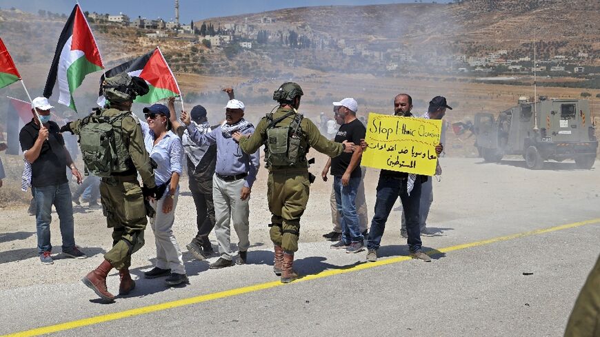 Israeli forces contain Palestinian protesters during a demonstration against settlement expansion, in the village of al-Mughayer, east of Ramallah in the occupied West Bank, on July 29, 2022