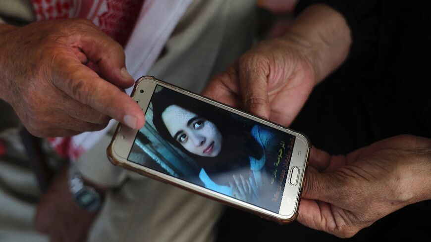 Palestinians Suleiman and Nazmiya Baraka display a picture of their daughter Istabraq, who was killed by her husband last year in the Gaza Strip