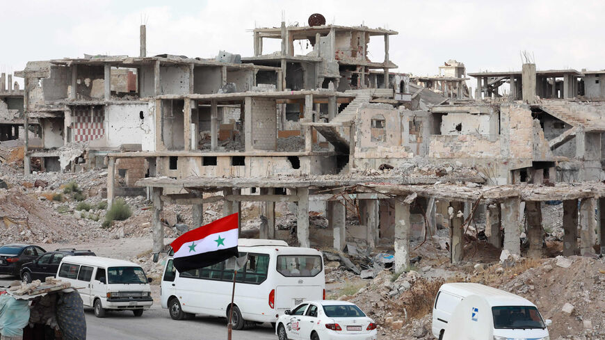 A picture taken during a tour organized by the Syrian Ministry of Information shows a Syrian national flag and cars in the district of Daraa al-Balad, Daraa, Syria, Sept. 12, 2021.