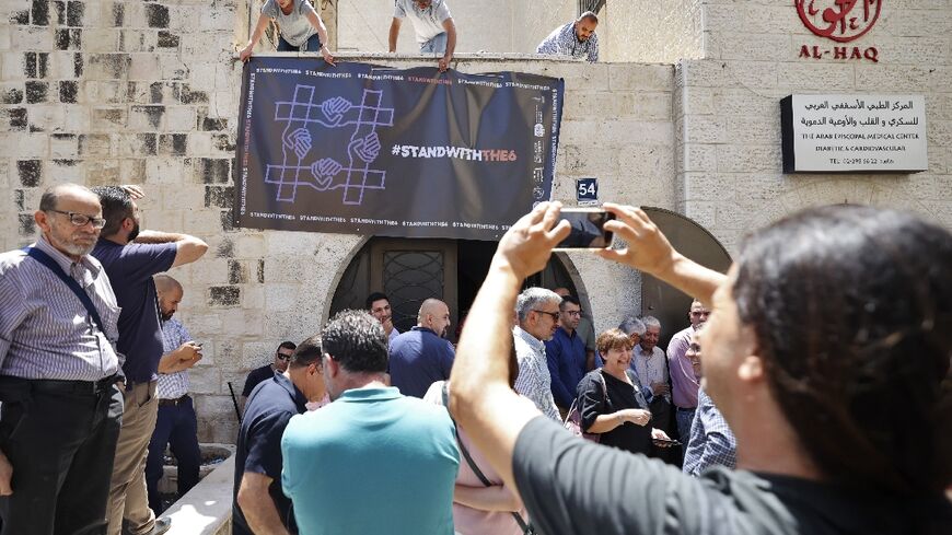 Activists hang a banner outside the Ramallah offices of Palestinian rights group Al-Haq after Israel troops raided them overnight and sealed the front door 