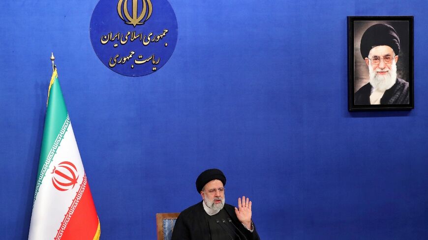 Iranian President Ebrahim Raisi sits near a portrait of Iran's Supreme Leader Ayatollah Ali Khamenei as he speaks during a press conference in Tehran on August 29, 2022