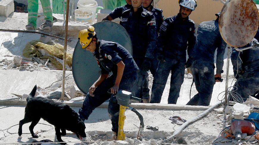 Jordanian rescue workers search for missing people under the rubble of a four-storey residential building which collapsed in central Amman