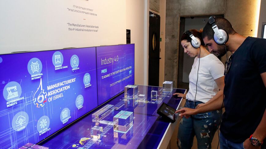 Visitors interact with a display by the Manufacturer's Association of Israel.