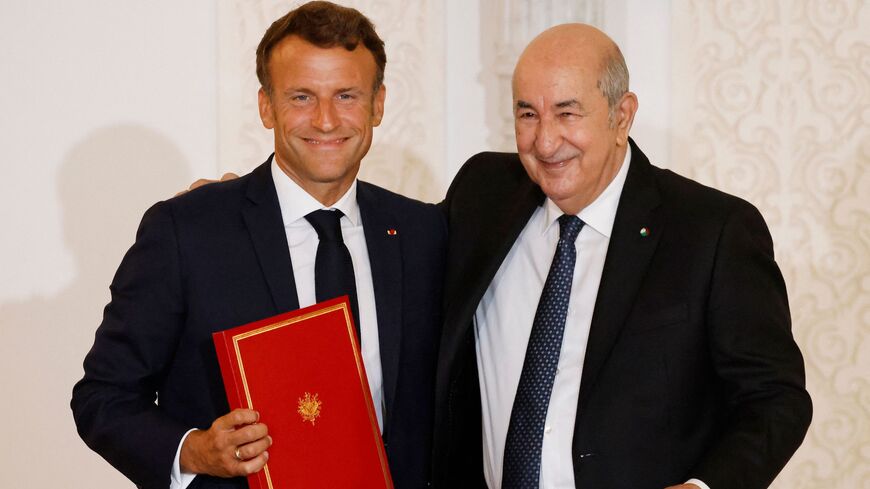 French President Emmanuel Macron (L) and Algeria's President Abdelmadjid Tebboune (R) attend a signing ceremony in the pavilion of honor at Algiers airport, in Algiers, on Aug. 27, 2022.