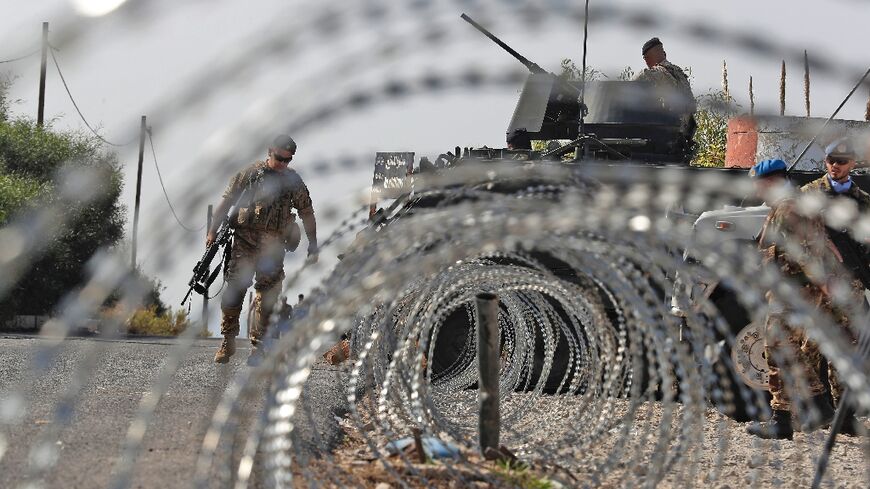 Lebanese army soldiers (L) stand by an infantry-fighting vehicle (IFV) near peacekeepers (R) of the United Nations Interim Force In Lebanon (UNIFIL) in Naqura along the border with northern Israel on Thursday