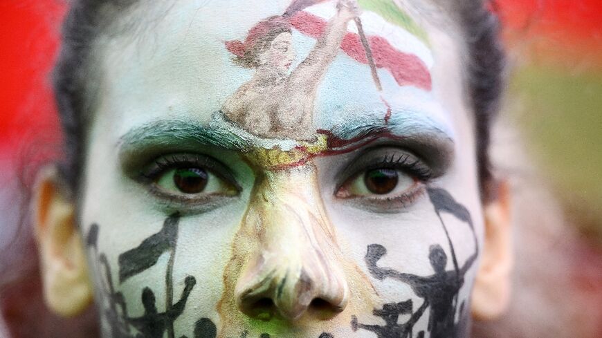 A protester wearing face-paint depicting France's iconic "Marianne" leading an uprising, attends a demonstration in support of Kurdish woman Mahsa Amini on October 2 in Paris