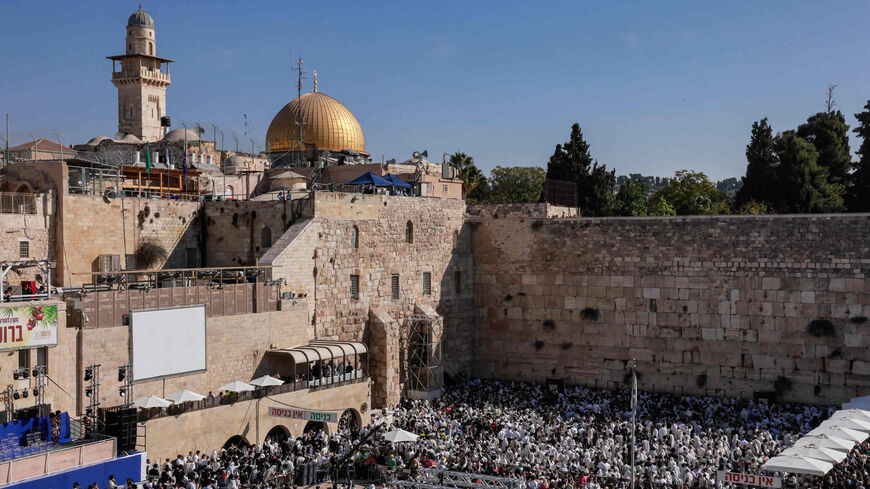 Jewish men, wearing traditional Jewish prayer shawls, gather to perform the annual Cohanim prayer during the holiday of Sukkot at the Western Wall (R), while above are seen the Muslim Dome of the Rock mosque (2nd-L) and its minaret (L), in the Old City of Jerusalem, Oct. 12, 2022.