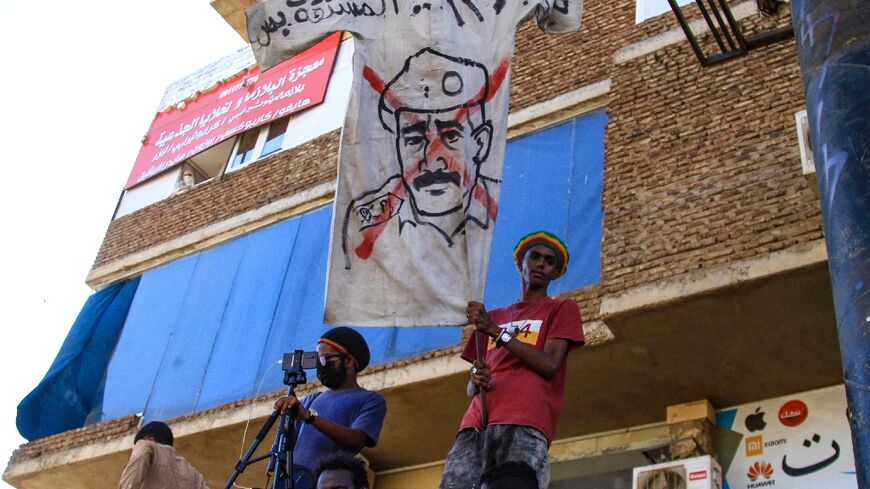 Sudanese protesters fly a banner bearing a crossed out image of coup leader Abdel Fattah al-Burhan, as they take to the streets to call for justice for those killed since last year's military power grab