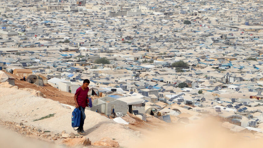 A young displaced Syrian returns from school to an overcrowded camp for the internally displaced near the village of Qah, close to the Turkish border, northwestern Idlib province, Oct. 28, 2020.