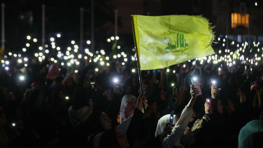 Supporters of Hezbollah hold up their phones and wave the party flag during a celebration marking the 40th anniversary of the Shiite movement creation in southern suburb of Beirut on Aug. 22, 2022.