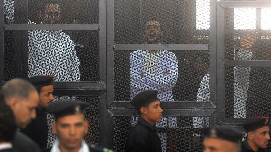 Egyptian activicts Mohamed Adel (L), Ahmed Douma (C) and Ahmed Maher (R) stand in the accused dock during their trial on December 22, 2013 in the capital Cairo. An Egyptian court sentenced three activists who spearheaded the 2011 uprising against Hosni Mubarak to three years in jail for organising an unlicensed protest, judicial sources said. It was the first such verdict against non-Islamist protesters since the overthrow of president Mohamed Morsi in July, and was seen by rights groups as part of a wideni