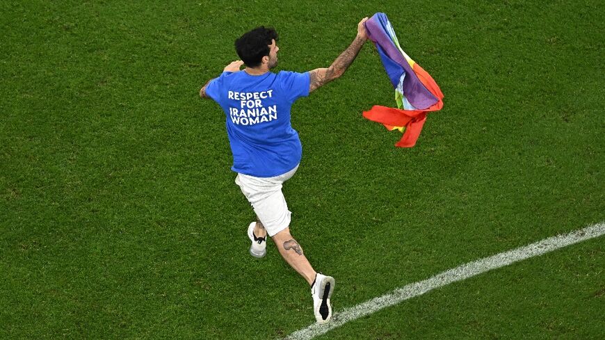 A man invades the pitch holding a rainbow flag in Qatar