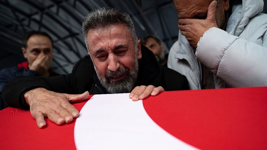 Nurettin Ucar (C) grieves over a flag-draped coffin at the funeral of his daughter Yagmur Ucar and ex-wife Arzu Ozsoy