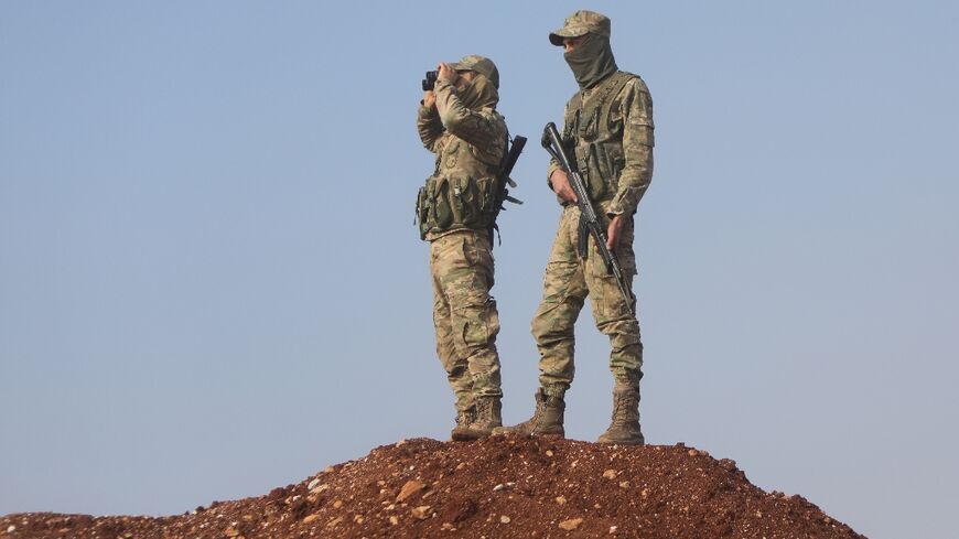 Turkish-backed Syrian fighters keep watch on the front line with Kurdish forces in Tal Rifaat, awaiting orders from Turkish President Recep Tayyip Erdogan on whether to proceed with a threatened ground offensive