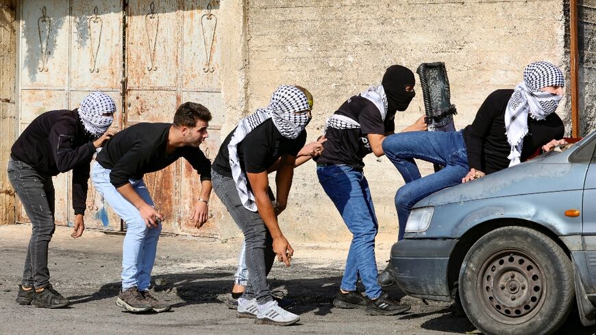 Palestinian demonstrators take cover during clashes with Israeli soldiers following a protest against the expropriation of Palestinian land by Israel in the village of Kfar Qaddum in the occupied West Bank, near the Jewish settlement of Kedumim