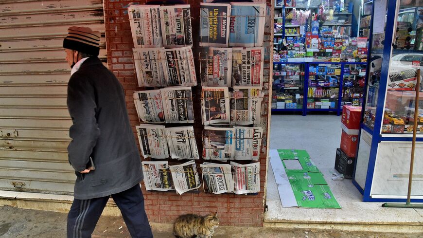 A man walks past a French-language daily newspaper stand displaying the final issue of Algerian French-language daily newspaper "Liberté" in Algeria's capital Algiers on April 14, 2022. (Photo by RYAD KRAMDI/AFP via Getty Images)