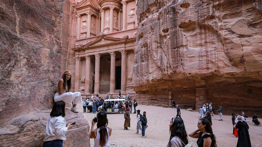 A tourist poses for a photo near the site of the Treasury at the ruins of the ancient Nabatean city of Petra in southern Jordan on on December 12, 2022. (Photo by KHALIL MAZRAAWI/AFP via Getty Images)