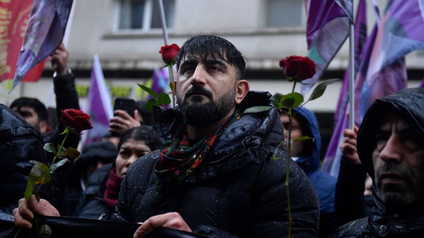 Protesters hold roses while taking part in a demonstration to pay tribute to the Enghien Street shooting victims in Paris on Dec. 23, 2022.