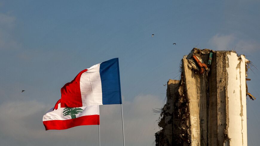 The flags of (front to back) France and Lebanon fly near the damaged grain silos at the port of Lebanon's capital Beirut on July 14, 2021, almost a year after the August 4 massive explosion that killed more than 200 people and injured scores of others. (Photo by PATRICK BAZ/AFP via Getty Images)