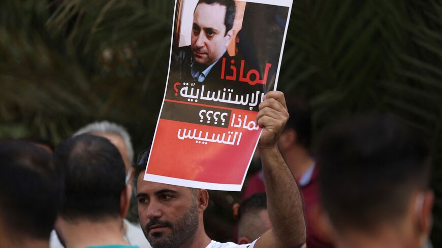 A supporter of Hezbollah and the Amal movements carries a portrait of Judge Tarek Bitar.