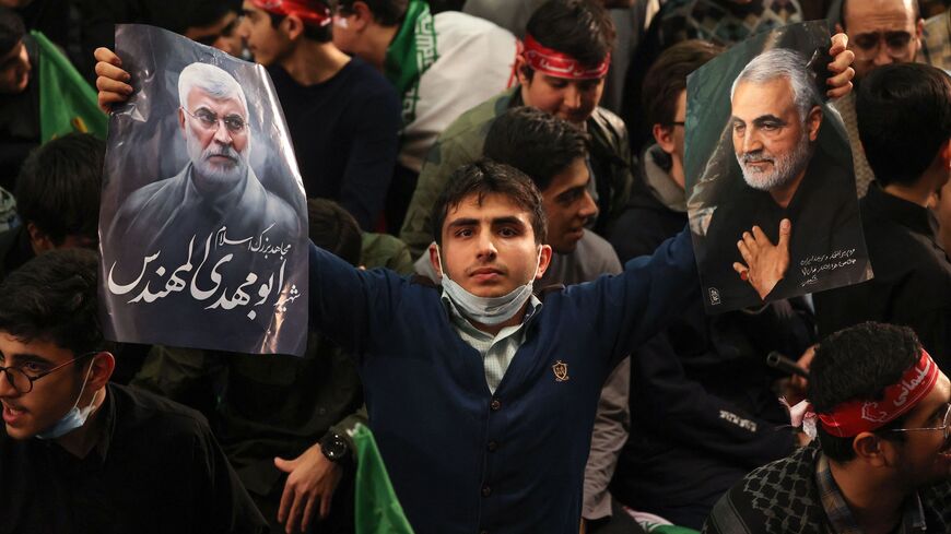 An Iranian carries the portraits of slain Iranian commander Qasem Soleimani and Iraqi commander Abu Mahdi al-Muhandis (L) during a ceremony in the capital Tehran, on January 3, 2023, to commemorate the third anniversary of their killing by a US drone strike in the Iraqi capital. (Photo by ATTA KENARE / AFP) (Photo by ATTA KENARE/AFP via Getty Images)