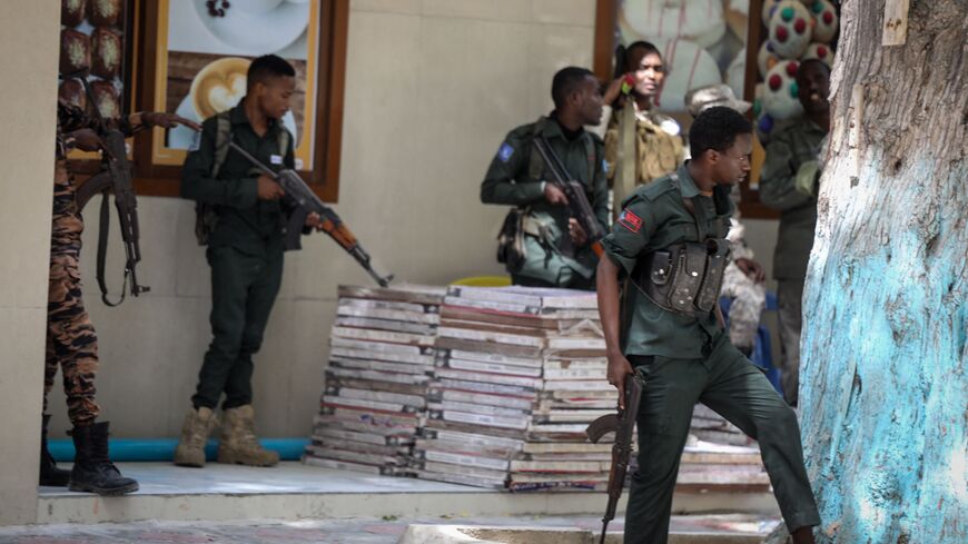 Police officers take up positions outside of the Mayor's office where an ongoing gun battle erupted following a reported explosion, in Mogadishu, on January 22, 2023. (Photo by HASSAN ALI ELMI/AFP via Getty Images)