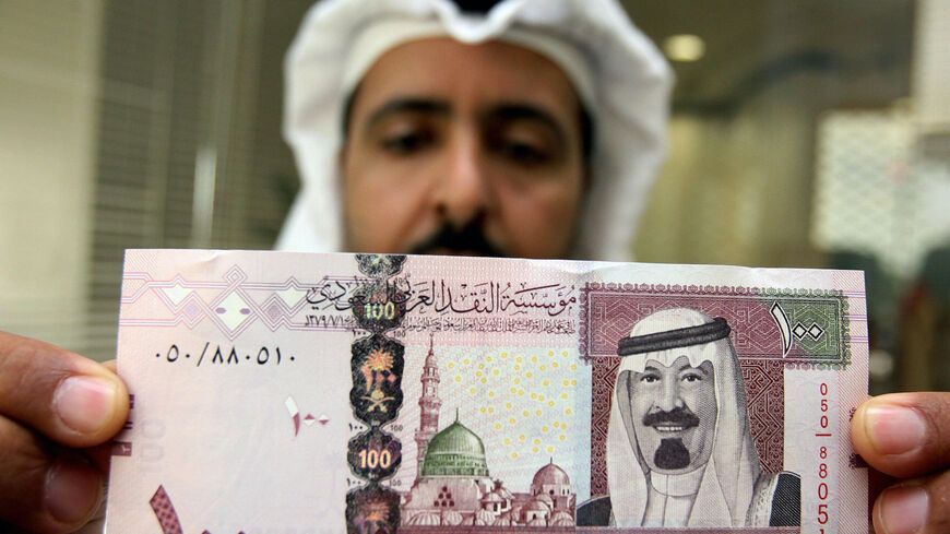 Riyadh, SAUDI ARABIA: A Saudi banker displays the new one hundred riyal banknote bearing the portrait of Saudi King Abdullah bin Abdul Aziz al-Saud at a bank in Riyadh, 05 June 2007. The banknotes featuring the king are the fifth issue released by the Saudi Arabian Monetary Agency (SAMA). AFP PHOTO/HASSAN AMMAR (Photo credit should read HASSAN AMMAR/AFP via Getty Images)