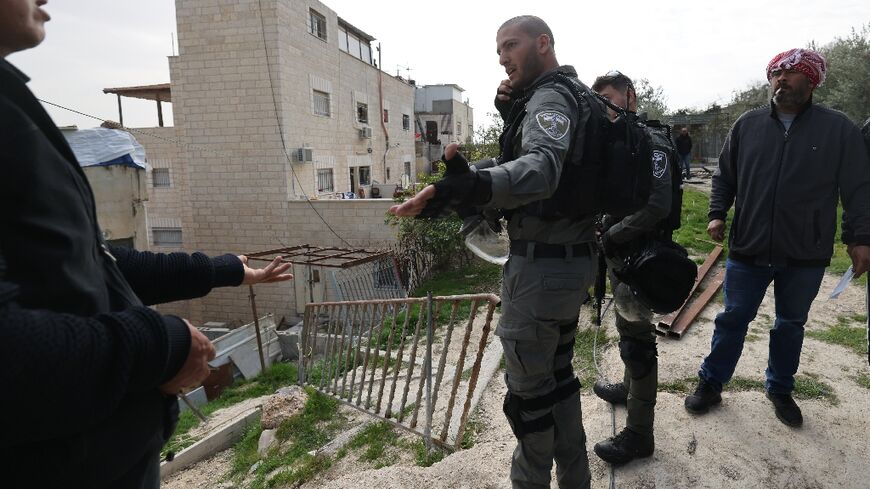 Israeli soldiers speak with relatives of Khayri Alqam, the gunman who killed seven people in an attack on Friday, as they prepare to demolish his home