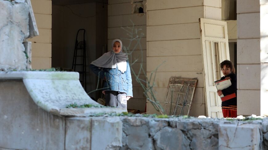 Two young girls stand in front of a building hit by a reported Israeli missile strike in Damascus, on February 19, 2023